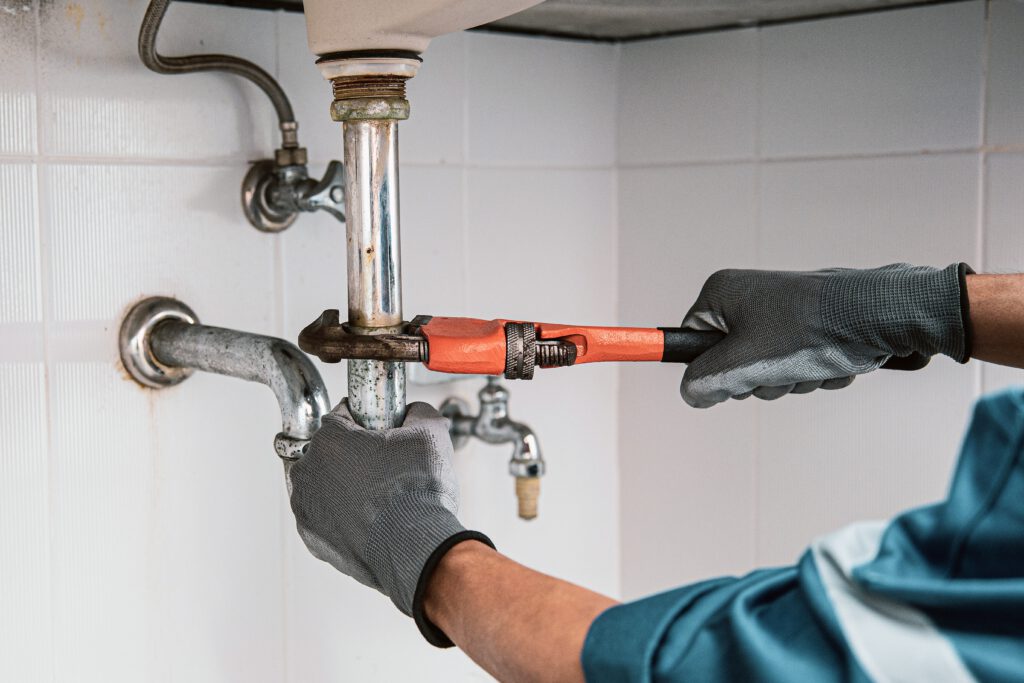 Plumber using wrench on water pipe.